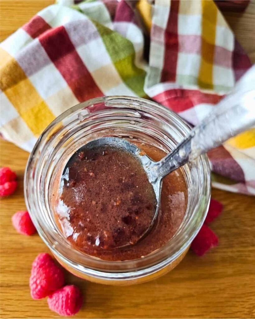 A jar of homemade raspberry vinaigrette with a spoon.